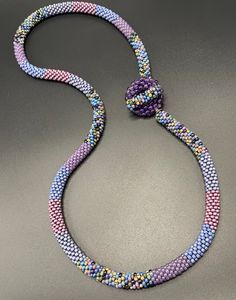 a multicolored beaded necklace on a gray surface