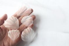 a person's hand holding several pieces of plastic wrapped in clear material on a white surface