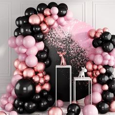 there is a large balloon arch with black and pink balloons in the center, along with other decorations