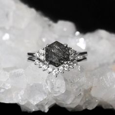 a black diamond ring sitting on top of some white crystals in front of a crystal cluster