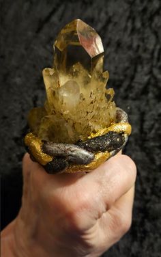 What a stunning piece of finger candy: I set a rare and scarce Smoky Citrine Record Keeper Quartz Tower into hand sculpted material, painted it, microglittered it and sealed it with a high gloss glaze. I attached a high quality, antique bronze adjustable mount to it which is wide, comfortable, secure and will adjust to fit most if not all. The ring measures 2.5" x 2" with a height of 3". A true showstopper from the Atelier of Kat Kouture! Magical Crystal Ring Gift, Handmade Nature-inspired Crystal Ring Gift, Handmade Nature-inspired Crystal Ring For Gift, Unique Resin Crystal Ring Gift, Artisan Carved Ring As A Gift, Artisan Carved Rings For Gift, Artisan Carved Ring As Gift, Artisan Carved Rings As Gifts, Unique Carved Rings As Gifts