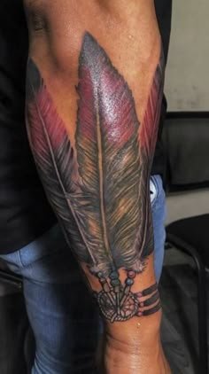 a man with a tattoo on his arm has a red and black feather in it