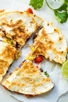 several quesadillas cut in half on top of paper with lime wedges