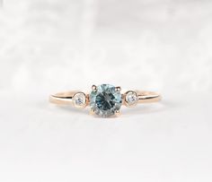 a blue diamond ring with three diamonds on the band and an oval stone in the middle