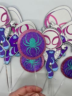 purple and blue cupcake toppers with an octopus on them are being held by a person's hand