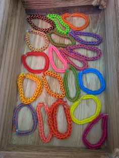 a wooden box filled with lots of different colored bracelets on top of a table