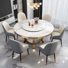 a white marble dining table surrounded by grey and beige chairs with gold trim around it