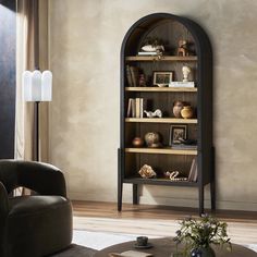 a living room filled with furniture and a tall book shelf next to a chair in front of a window