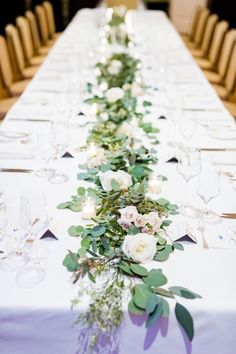 a long table with white flowers and greenery