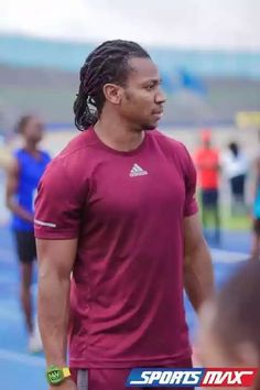 a man with dreadlocks standing on a blue track in front of other people