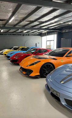 there are many different colored sports cars in this garage, all lined up and ready to be driven