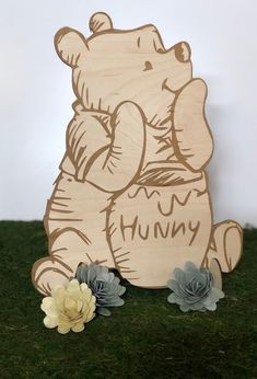 a wooden sign with an image of a teddy bear holding the word humm on it