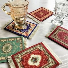 four coasters with different designs on them and one has a glass in the middle