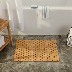 a bath room with a toilet and a bath tub next to a towel rack on the floor