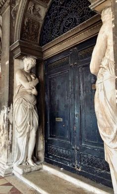 two statues standing next to each other in front of a door