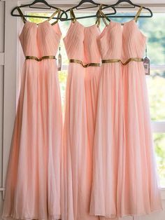 four bridesmaid dresses hanging in front of a window