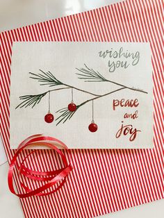 a red and white striped card with a christmas ornament hanging from it's side