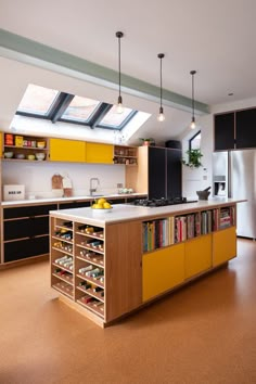 a kitchen with yellow cabinets and an island in the middle is lit by two skylights