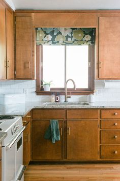 a kitchen with wooden cabinets and white tile backsplash, window over the sink