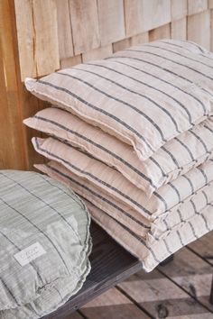 four pillows stacked on top of each other next to a wooden bench in front of a wall