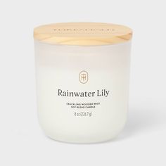 a white candle with a wooden lid and the words rainwater lily written on it