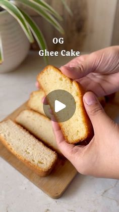 a person holding a piece of bread on top of a cutting board