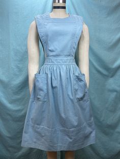 "1940s W:25 Angelica vintage pinafore sleeveless apron uniform dress pockets canvas cotton linen sanforized blue aqua button up square neck fit flare  Great 40s uniform dress from Angelica. Classic uniform pinafore silhouette of sleeveless bib with gathered flare skirt. Reinforced armholes, neckline and waistline. Button down with white buttons in the back. Two slanted oversized front pockets. Sanforized canvas cotton linen fabric in sweet shade of vintage blue aqua contrasted. Photographed on f Vintage Square Neck Dress, Sleeveless Cotton Apron With Pockets, Cotton Apron With Pockets, Cotton Workwear Apron With Pockets, Blue Cotton Pinafore Dress With Pockets, Solid Color Vintage Cotton Dress, Vintage Fitted Pinafore Dress, Fitted Sleeveless Cotton Pinafore Dress, Fitted Cotton Pinafore Dress For Work