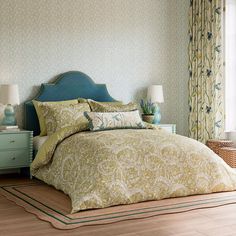 a bedroom with blue headboard and yellow comforter on the bed in front of a window