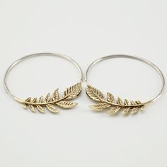 • Pair of Olive Leaf Hoop Earrings. • Cascade of gold-tone leaves w/ solid 925 sterling hoops. • 1" diameter hoops. • Backings Included. Do you have a nature lover in your life? The olive leaf earrings make a great gift! These earrings feature a sweet cascade of solid brass leaves with small 925 silver (hypoallergenic) hoops. The olive branch has been worldwide symbol of peace since ancient times, while the circle symbolizes wholeness. Give a gift of peace and wholeness. Silver Tarnish Resistant Hoop Earrings In Brass, Cadmium-free Hoop Brass Jewelry, Cadmium-free Brass Hoop Jewelry, Hypoallergenic Silver Hoop Earrings In Brass, Metal Hoop Earrings With Ear Wire For Anniversary, The Olive Branch, Peace Earrings, Symbol Of Peace, Gold Leaf Earrings