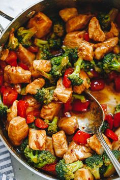 chicken and broccoli stir fry in a pan with a spoon