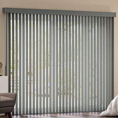 a living room with wooden floors and sliding glass doors that have vertical blinds on them