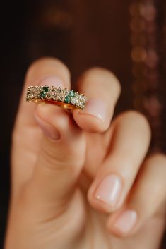 a woman's hand holding an emerald and diamond ring