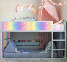 a child's bedroom with a rainbow colored bunk bed and pink curtains on the ceiling