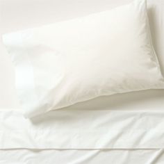 an unmade bed with white sheets and pillows