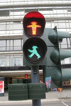 a traffic light with an image of a person crossing the street in front of a building