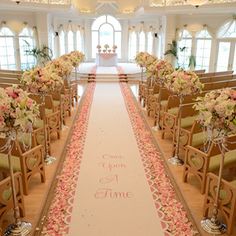 the aisle is decorated with pink flowers and greenery for a wedding ceremony in an elegant setting