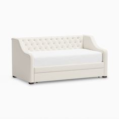 a white couch sitting on top of a white floor next to a bed with pillows