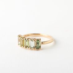 three stone ring in yellow gold with green tourmaline stones on the sides and diamond accents