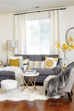 a living room filled with furniture and flowers on top of a wooden floor next to a window