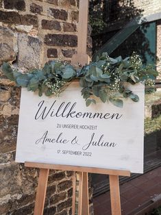 a wooden sign with greenery on it in front of a brick wall