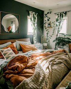 an unmade bed in a bedroom with plants on the wall and mirror above it