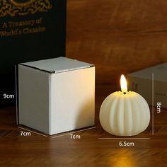 a white candle sitting on top of a wooden table next to a box with a light inside