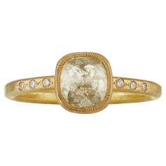 a yellow gold ring with an oval cut diamond in the center and small diamonds around it