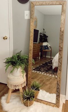 a large mirror sitting on top of a wooden floor next to a potted plant