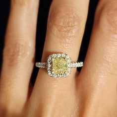 a woman's hand with a yellow and white diamond ring on top of it