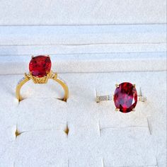 two red rings sitting on top of a white box next to another ring with diamonds