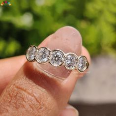 a person holding a ring with five diamonds on it