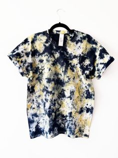 a black and yellow tie dye t - shirt hanging on a hanger