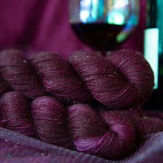 several skeins of yarn sitting next to a bottle of wine