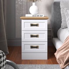 a white night stand with three drawers in front of a bed